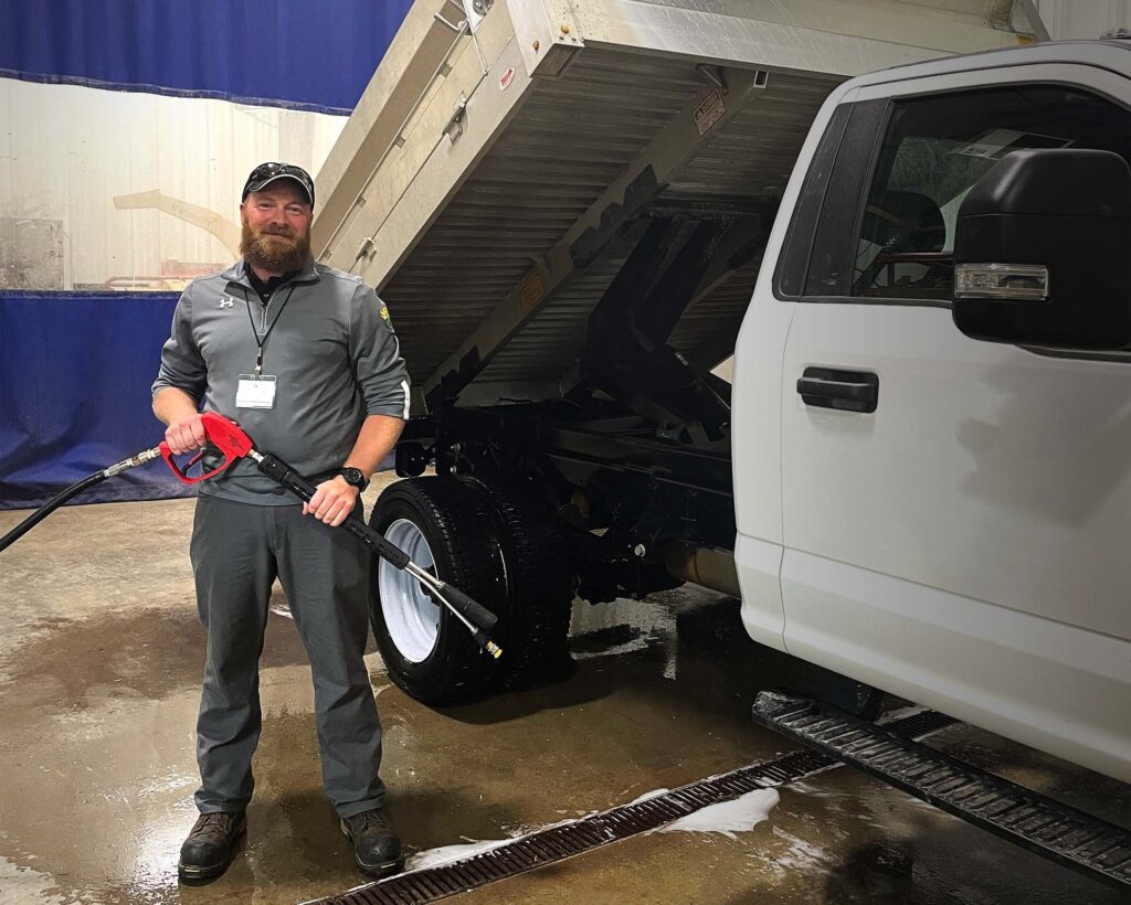 man posing for picture after washing work truck