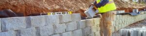 Landscaper laying cinder blocks in a retaining wall.