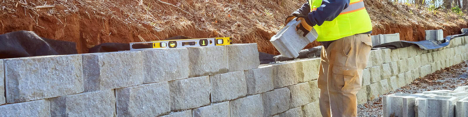 Landscaper laying cinder blocks in a retaining wall.